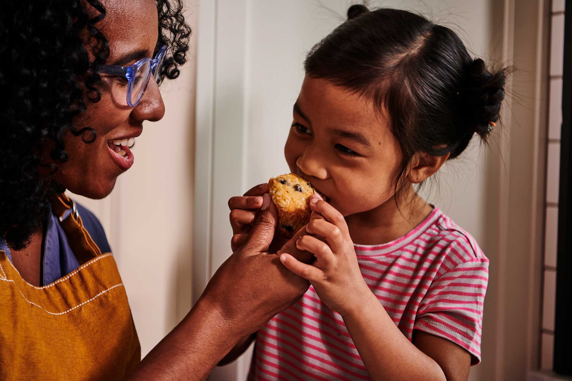 Child taking a bite of a Krusteaz Wild Blueberry muffin